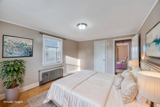 bedroom with light hardwood / wood-style flooring, crown molding, and radiator heating unit