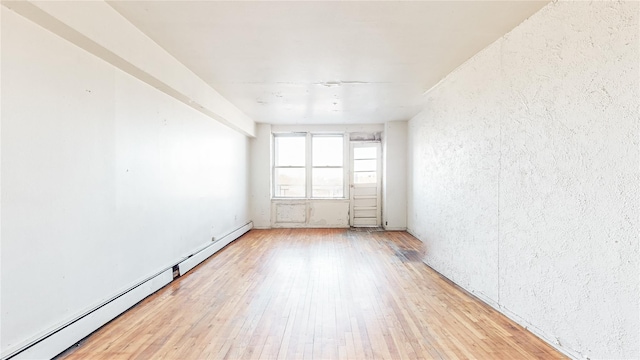 spare room with wood-type flooring and a baseboard heating unit