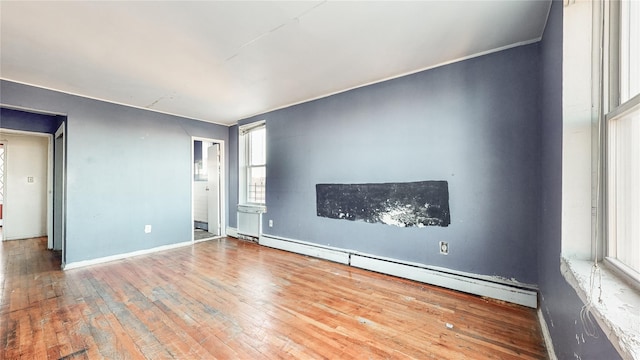 spare room featuring baseboard heating and hardwood / wood-style flooring