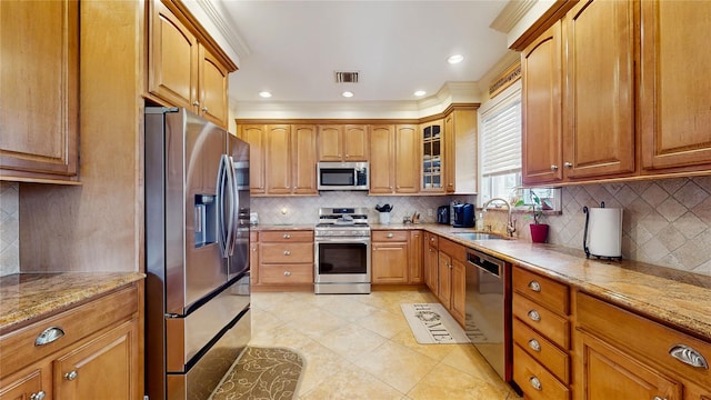 kitchen with visible vents, glass insert cabinets, appliances with stainless steel finishes, ornamental molding, and a sink