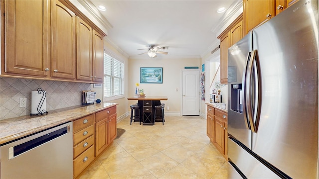 kitchen with decorative backsplash, appliances with stainless steel finishes, ornamental molding, ceiling fan, and baseboards