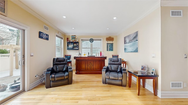 office space with light wood finished floors, ornamental molding, visible vents, and baseboards