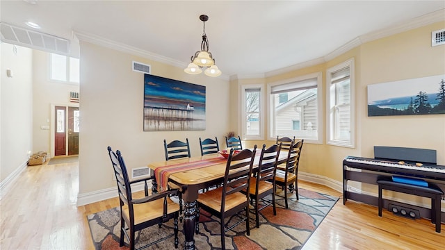 dining space featuring light wood-type flooring, visible vents, and crown molding