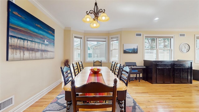 dining space with light wood-style floors, visible vents, and crown molding