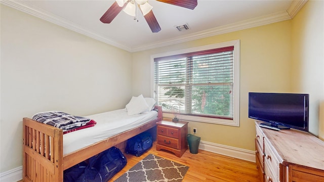 bedroom with baseboards, visible vents, ceiling fan, crown molding, and light wood-type flooring