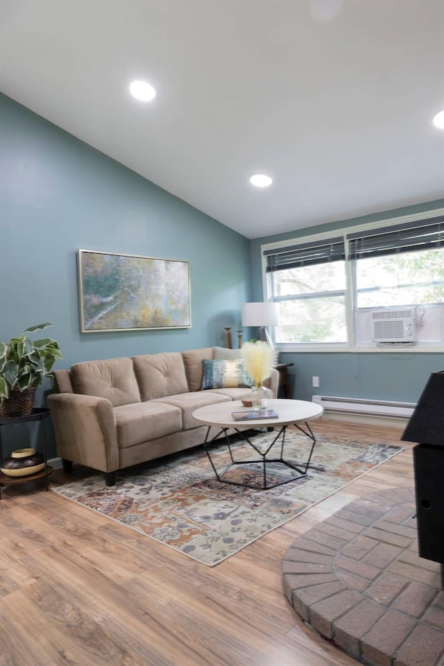 living room featuring lofted ceiling, cooling unit, a baseboard heating unit, and hardwood / wood-style floors