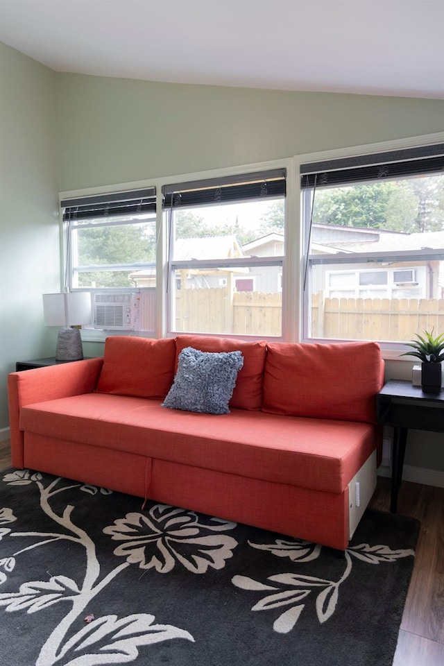 living room featuring cooling unit, vaulted ceiling, a healthy amount of sunlight, and dark wood-type flooring