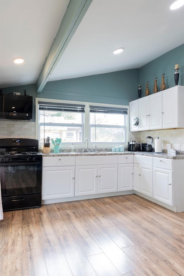 kitchen with black range with gas cooktop, tasteful backsplash, and white cabinetry