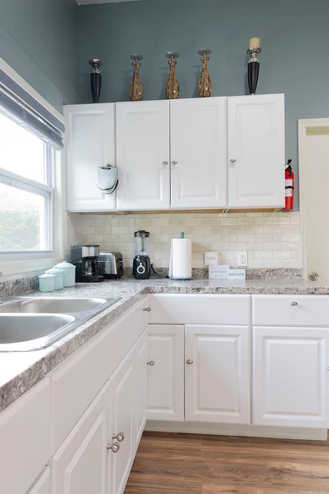 kitchen with sink, wood-type flooring, white cabinetry, and tasteful backsplash