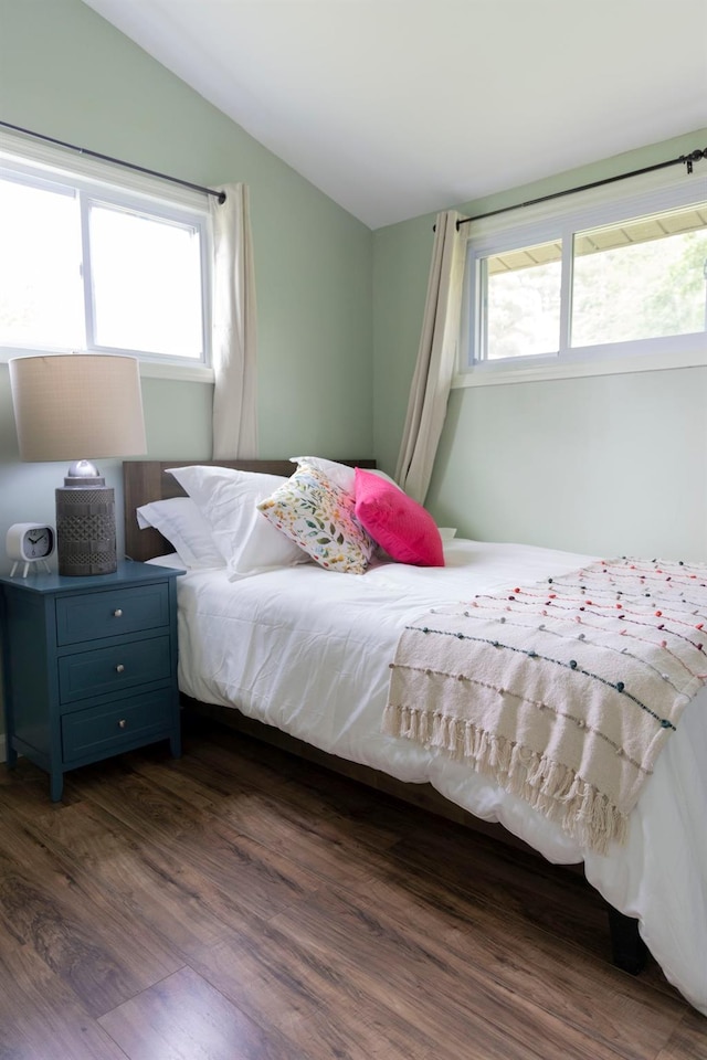 bedroom featuring dark wood-type flooring, vaulted ceiling, and multiple windows