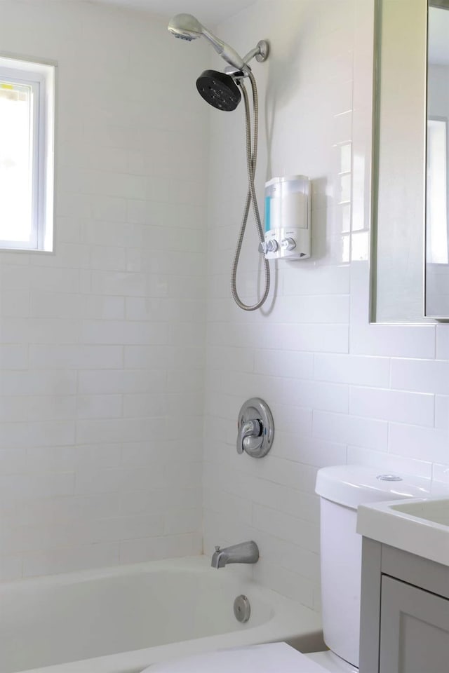 full bathroom with tiled shower / bath combo, vanity, and toilet