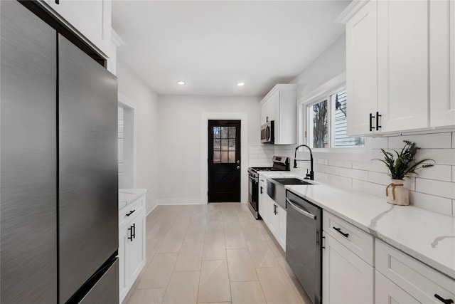 kitchen with sink, white cabinets, light stone counters, tasteful backsplash, and appliances with stainless steel finishes