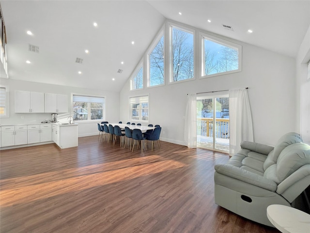 living room with dark wood-type flooring, sink, and high vaulted ceiling