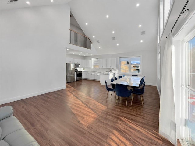 dining space with high vaulted ceiling, dark wood-type flooring, and sink