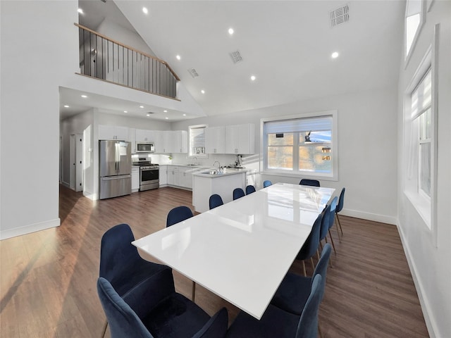 dining area with high vaulted ceiling, dark wood-type flooring, and sink