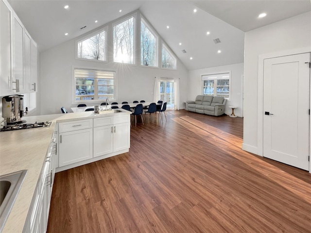 kitchen featuring sink, stainless steel gas cooktop, dark wood-type flooring, high vaulted ceiling, and white cabinets