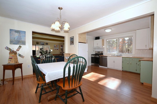 dining area featuring hardwood / wood-style flooring, ornamental molding, sink, and a chandelier