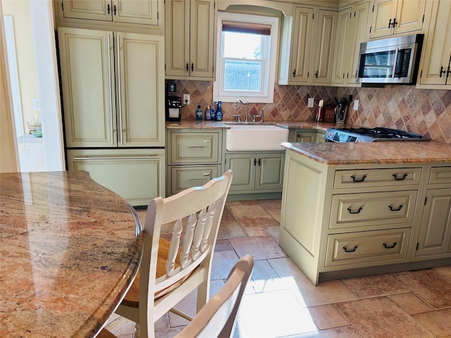 kitchen featuring tasteful backsplash, paneled built in refrigerator, sink, and cream cabinetry