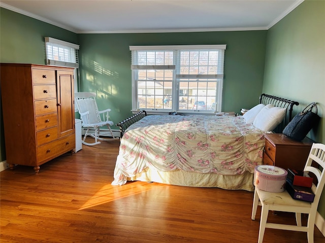 bedroom with ornamental molding, wood-type flooring, and multiple windows