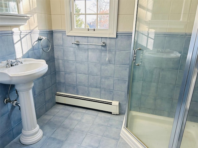 bathroom with a shower with door, tile patterned flooring, a baseboard heating unit, and tile walls