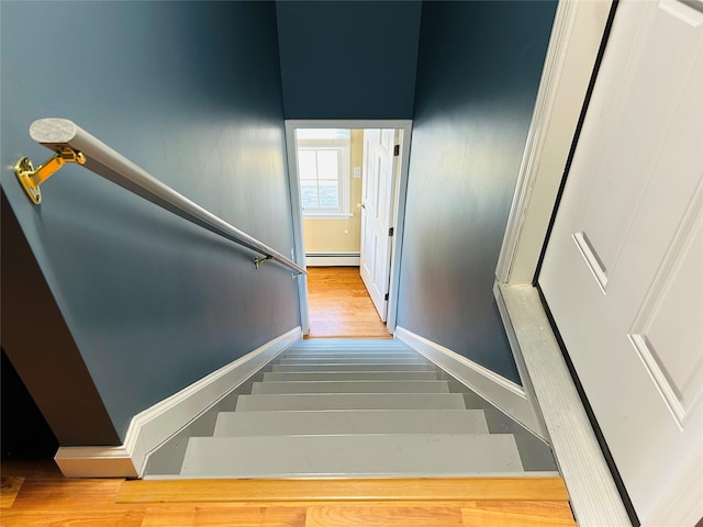 stairs with hardwood / wood-style floors and a baseboard radiator