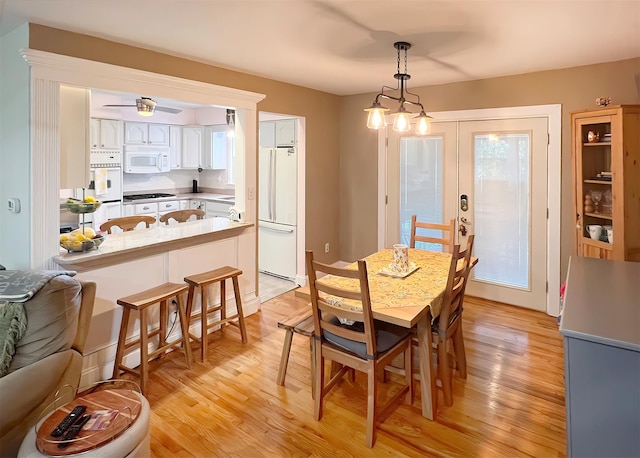 dining space featuring light hardwood / wood-style floors, french doors, and an inviting chandelier