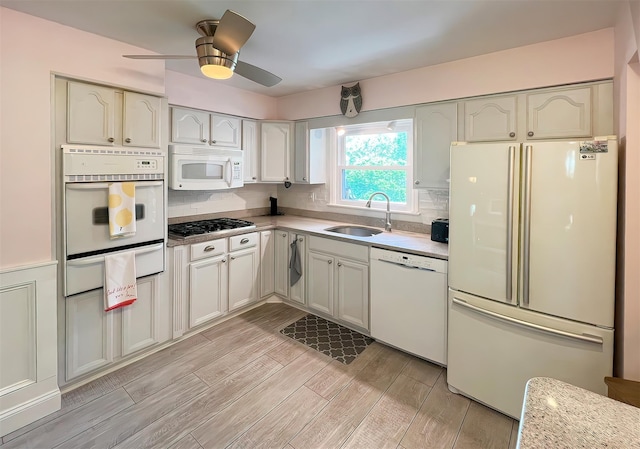 kitchen featuring ceiling fan, tasteful backsplash, sink, white appliances, and white cabinetry