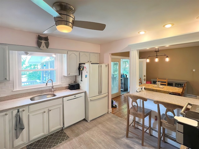 kitchen with white appliances, white cabinets, tasteful backsplash, and sink