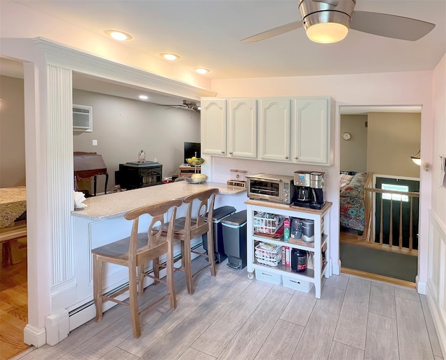 kitchen with ceiling fan, a wall mounted AC, and white cabinetry