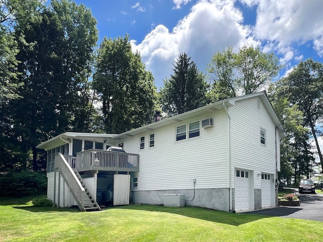 back of house with a wall unit AC, a lawn, cooling unit, a wooden deck, and a garage