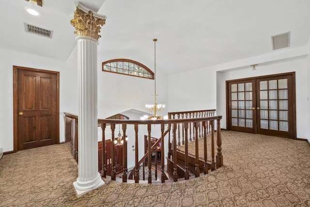 hall with french doors, lofted ceiling, decorative columns, an inviting chandelier, and carpet