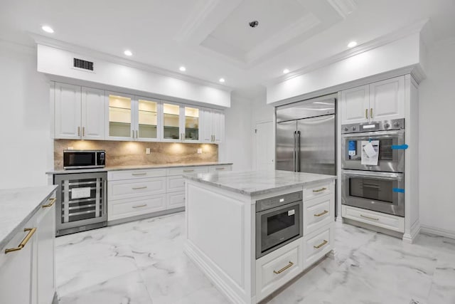 kitchen with appliances with stainless steel finishes, white cabinets, a center island, and wine cooler