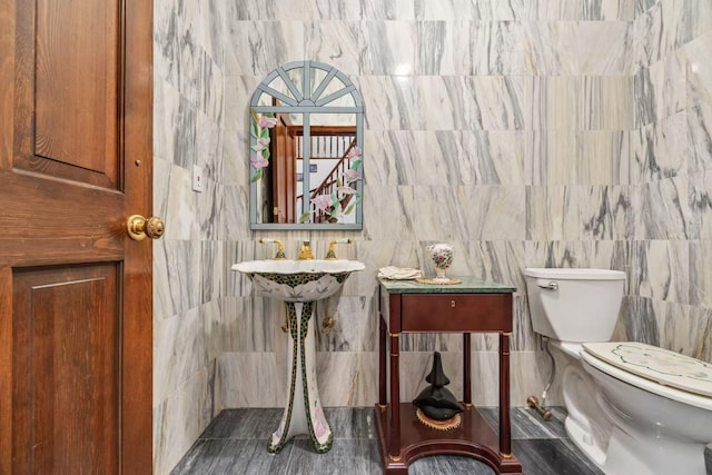 bathroom with toilet and tile walls