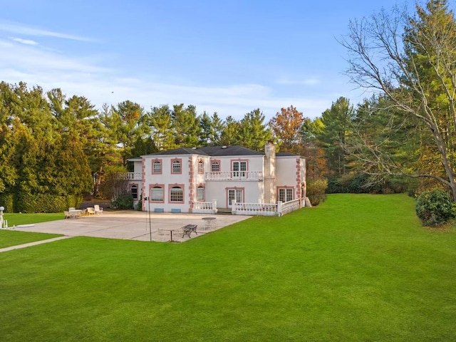 back of house featuring a balcony, a patio, french doors, and a yard