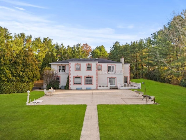 back of property featuring a balcony, a lawn, french doors, and a patio area