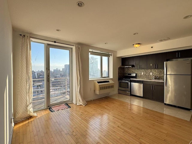 kitchen with backsplash, sink, light hardwood / wood-style flooring, heating unit, and stainless steel appliances