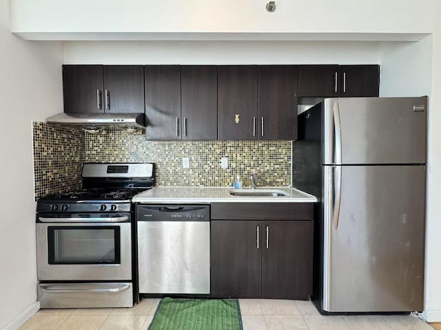 kitchen with appliances with stainless steel finishes, dark brown cabinetry, sink, backsplash, and light tile patterned floors