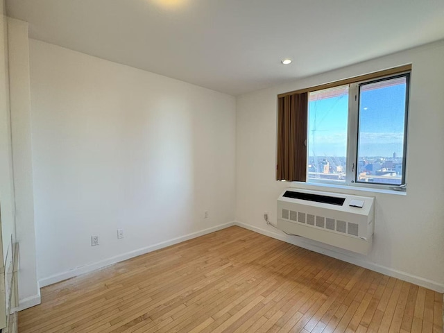 spare room featuring a wall unit AC and light hardwood / wood-style flooring