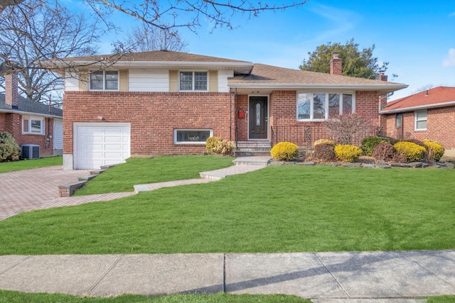 split level home featuring central AC, a front lawn, and a garage