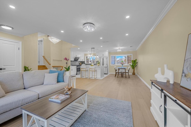 living room featuring light hardwood / wood-style flooring, ornamental molding, and an inviting chandelier