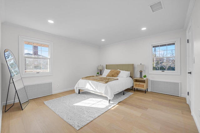 bedroom with radiator heating unit, ornamental molding, and light wood-type flooring