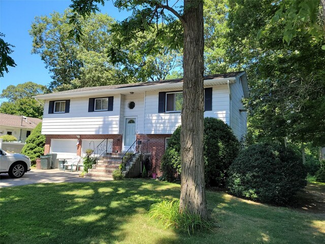 split foyer home featuring driveway, a garage, a front lawn, and brick siding