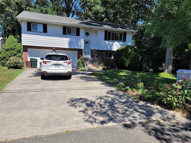 split foyer home featuring a garage, driveway, brick siding, and a front yard