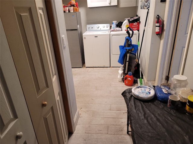 clothes washing area with laundry area, light wood-type flooring, and washing machine and dryer