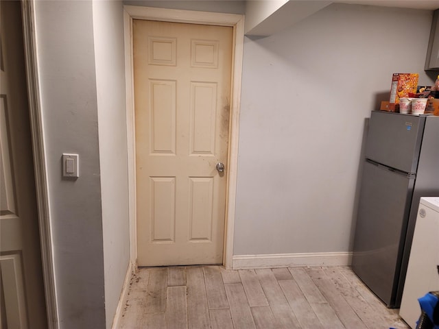 kitchen with light wood-type flooring, freestanding refrigerator, light countertops, and baseboards