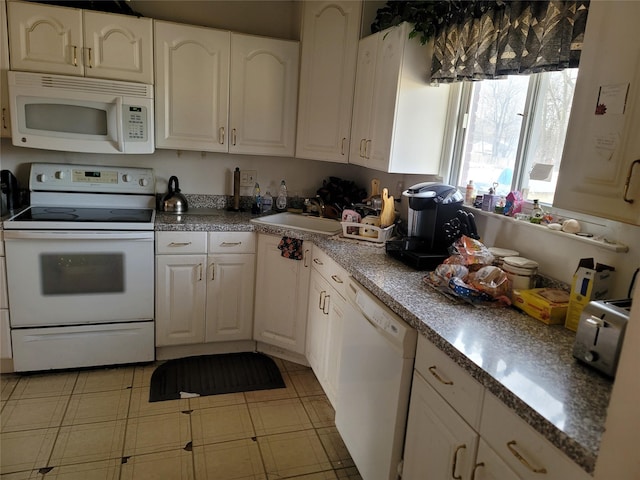 kitchen with dark countertops, white appliances, white cabinetry, and a sink