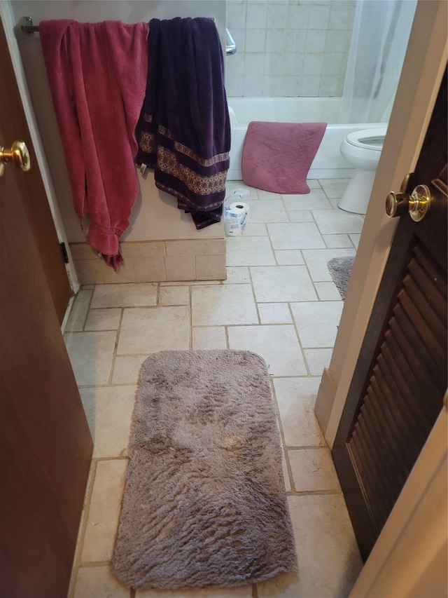 full bath with stone tile flooring and toilet