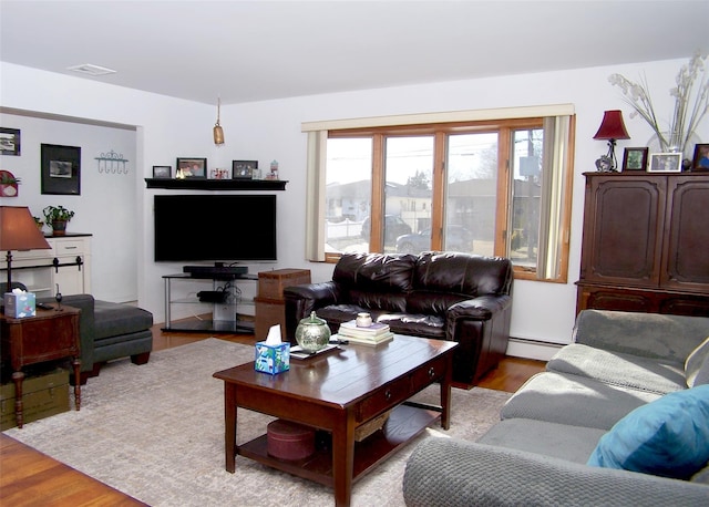 living room with a baseboard heating unit and light hardwood / wood-style floors