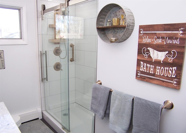 bathroom featuring a baseboard heating unit, a shower with shower door, and tile patterned floors