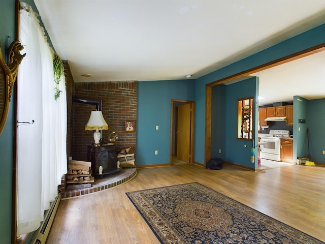 interior space with wood-type flooring, vaulted ceiling, a baseboard radiator, and a wood stove